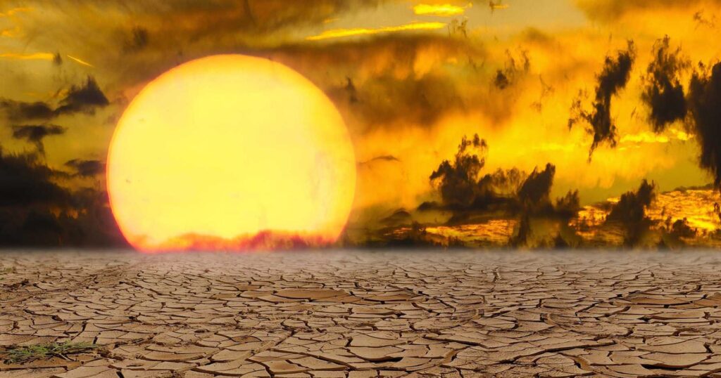 A sun setting on a desert land affected by drought due to climate change